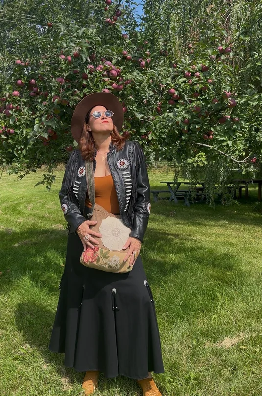 Femme en veste de cuir à franges et chapeau devant un pommier — Collection automne Honeybou