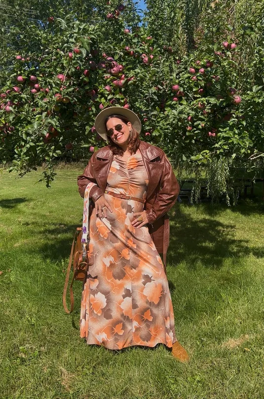 Femme en robe fleurie et veste de cuir brun devant un pommier — Collection automne Honeybou